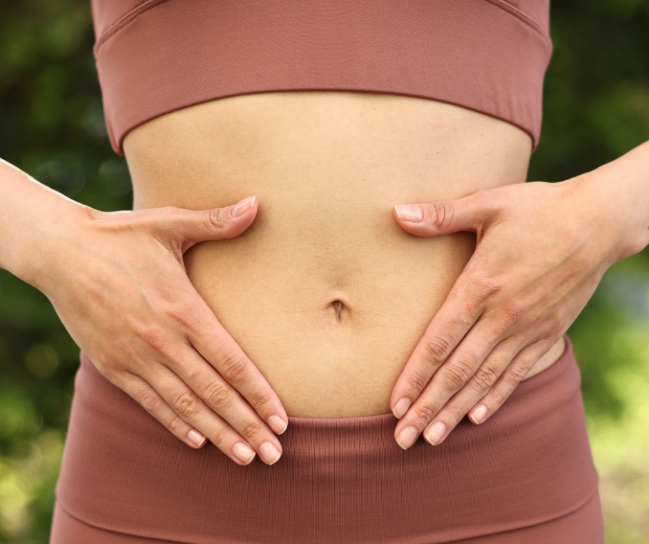 Femme posant les mains sur son ventre pour symboliser l’équilibre du microbiote intestinal à la ménopause, clé d’un système immunitaire fort et d’une digestion saine naturellement.
