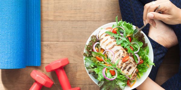 Assiette équilibrée, haltères et tapis de yoga illustrant une hygiène de vie saine à la ménopause pour renforcer le système immunitaire, gérer le stress et préserver l’énergie naturellement.