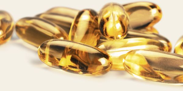 Capsules dorées de compléments alimentaires naturels riches en oméga-3 et vitamines, idéales pour renforcer le système immunitaire et soutenir la vitalité des femmes à la ménopause.